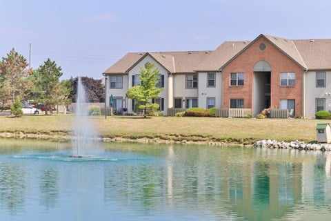a fountain in a pond with a building in the background