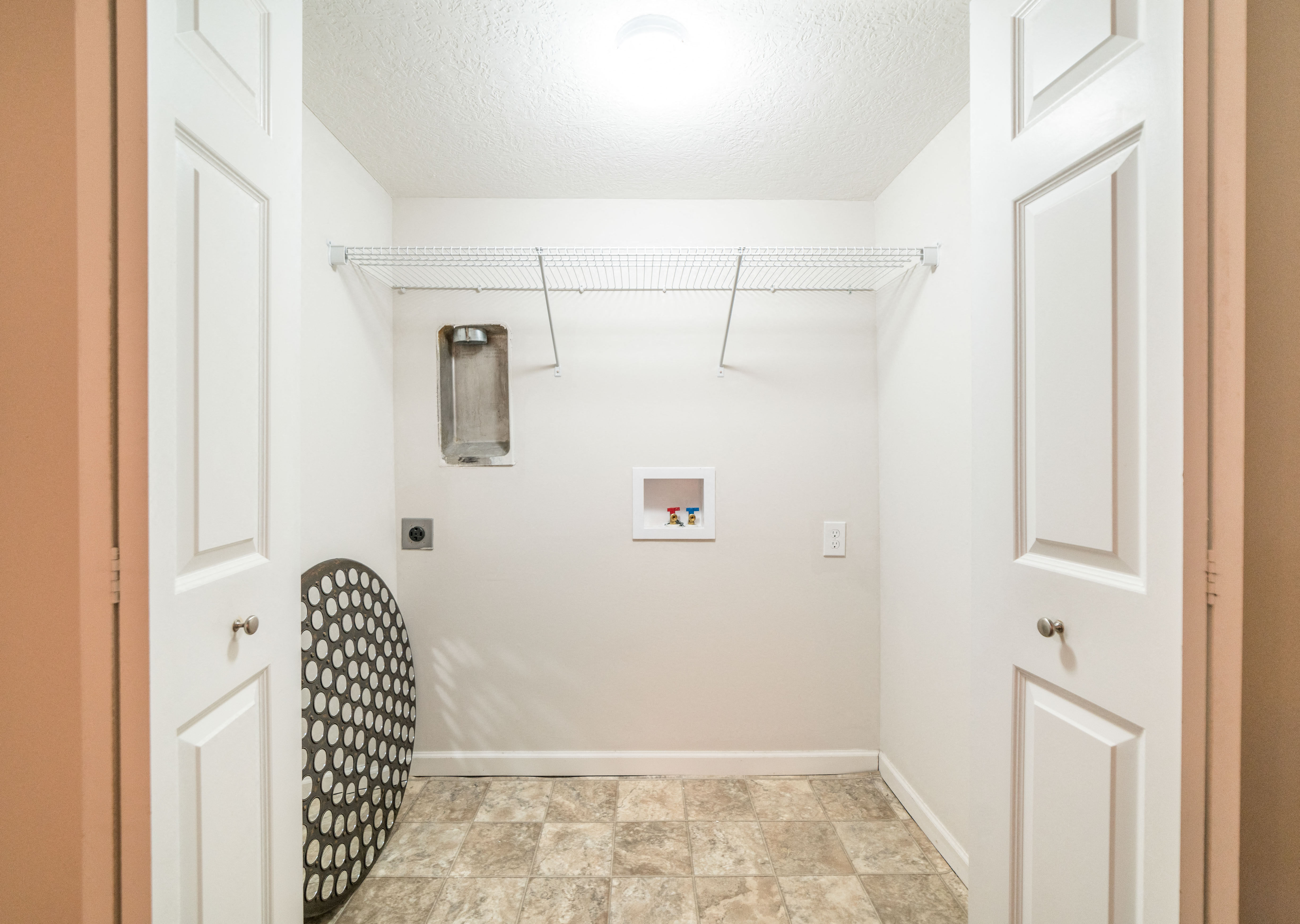 a laundry room with white walls and white doors and a closet with a hanger