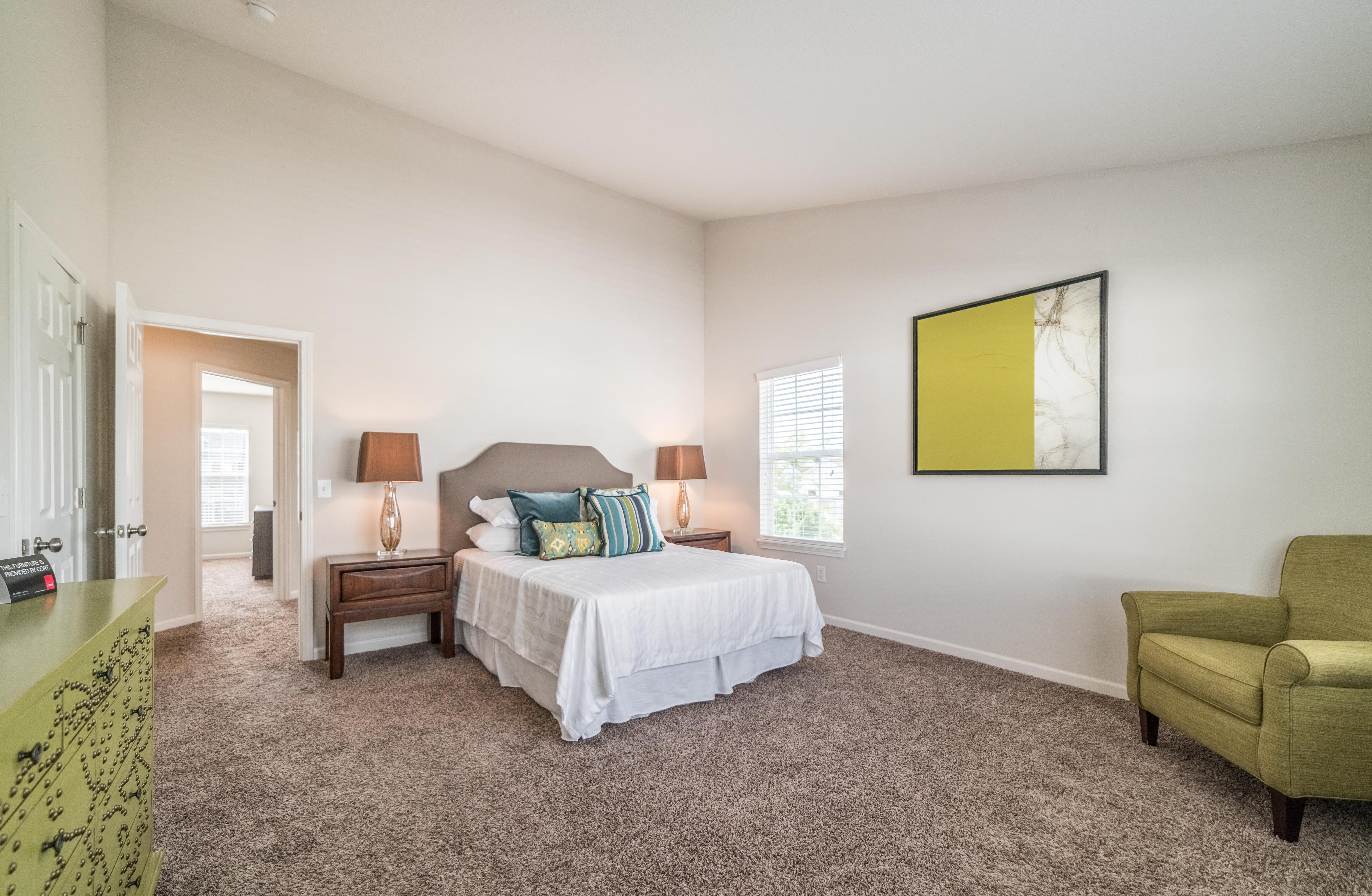 a bedroom with a white bed and a green chair