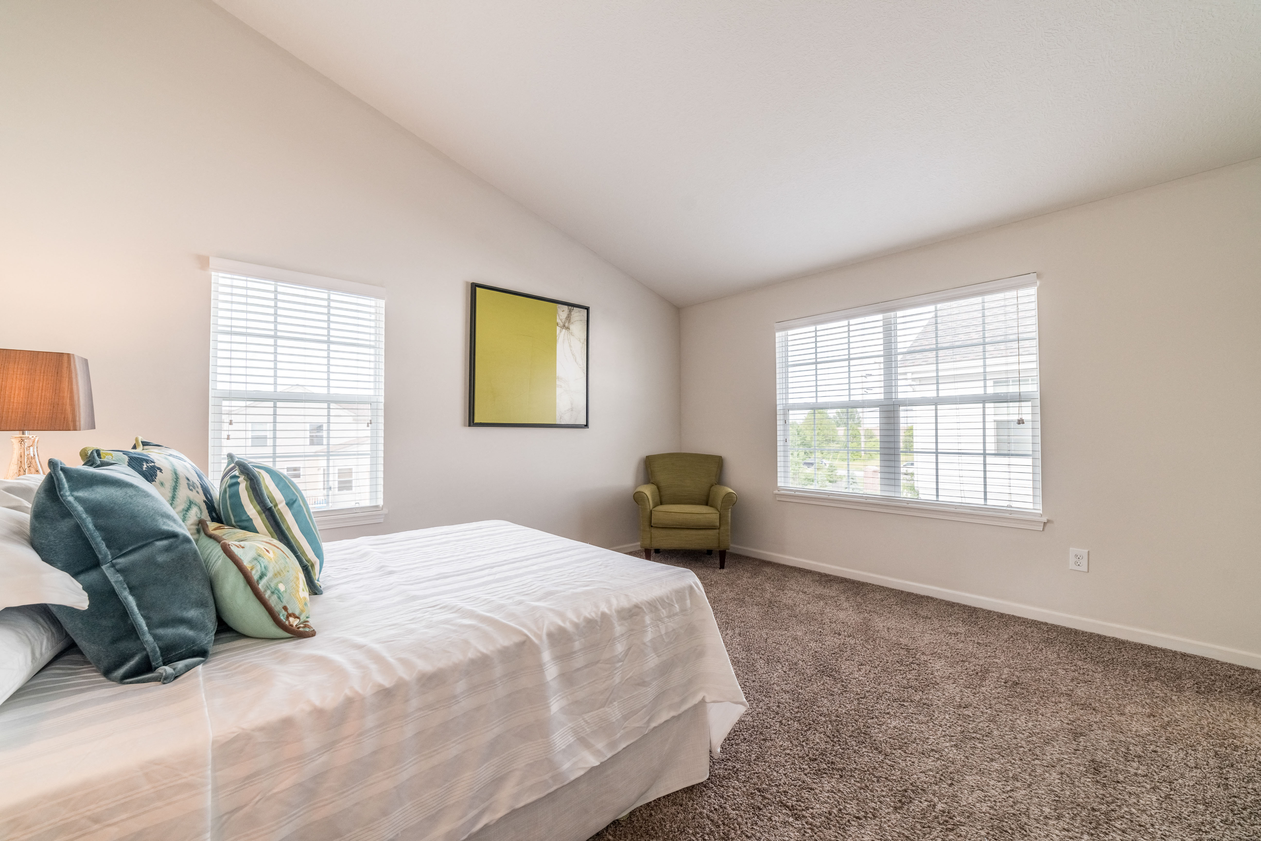 a bedroom with a white bed and two windows