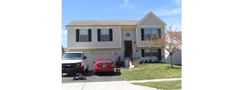 A two-story house with a red car parked in front.