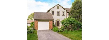 A house with a white garage door and a brown door.
