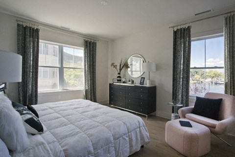 a bedroom with a bed and a dresser and windows