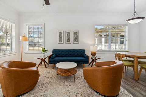 A living room with a blue couch and brown chairs.