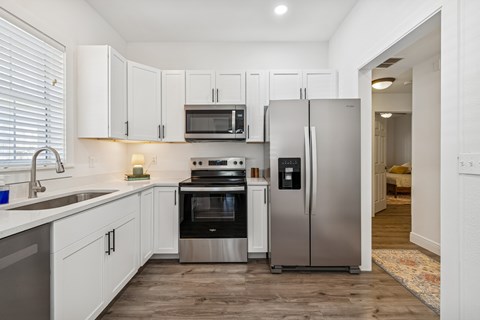 A modern kitchen with white cabinets and stainless steel appliances.