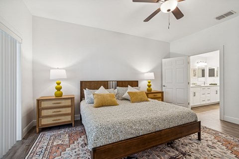 A bedroom with a bed, nightstand, and a ceiling fan.