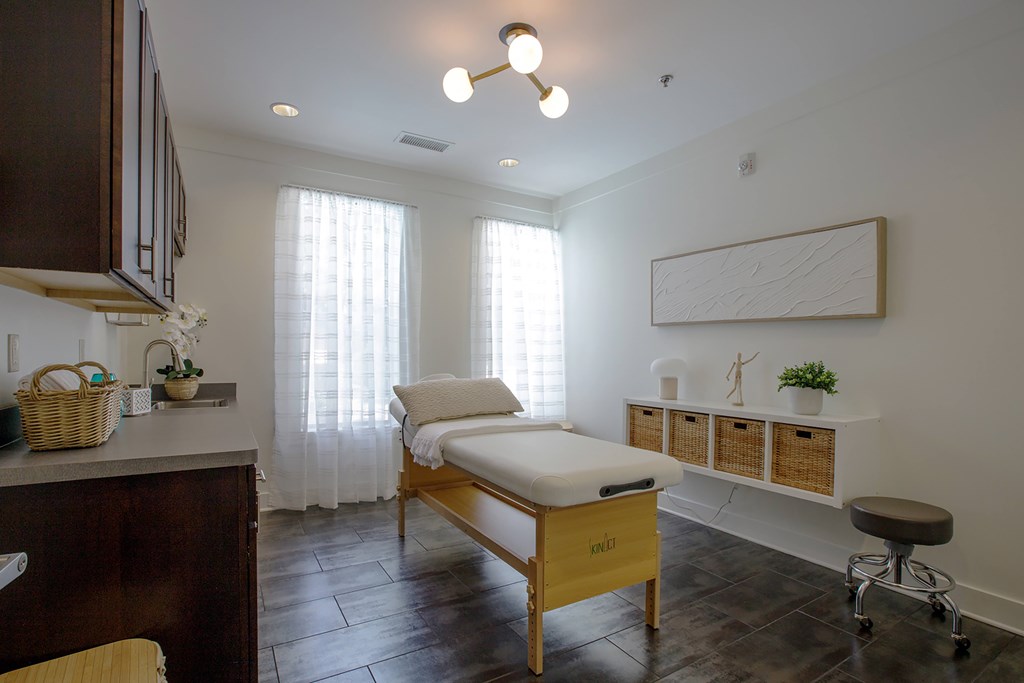 A room with a massage table and a window with curtains.
