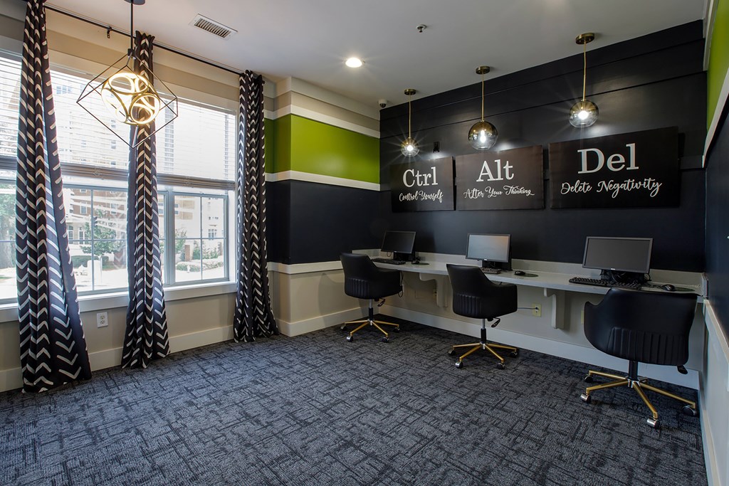 A room with a desk and chairs with a sign that says "Ctrl", "Alt", and "Del" on the wall.