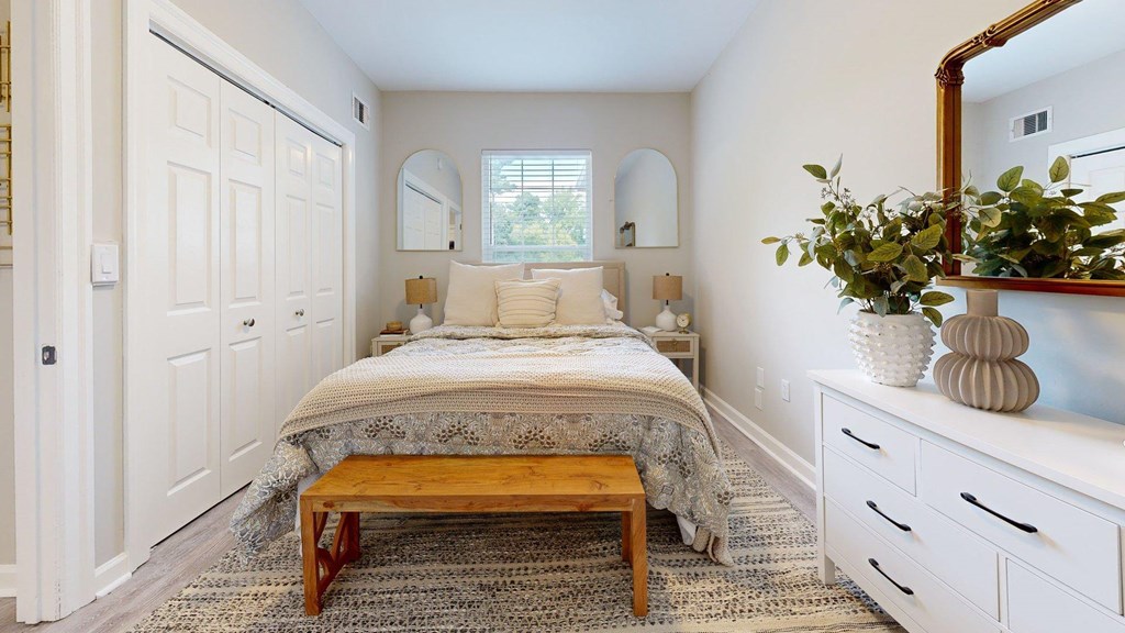 A bedroom with a bed, a bench, and a mirror.