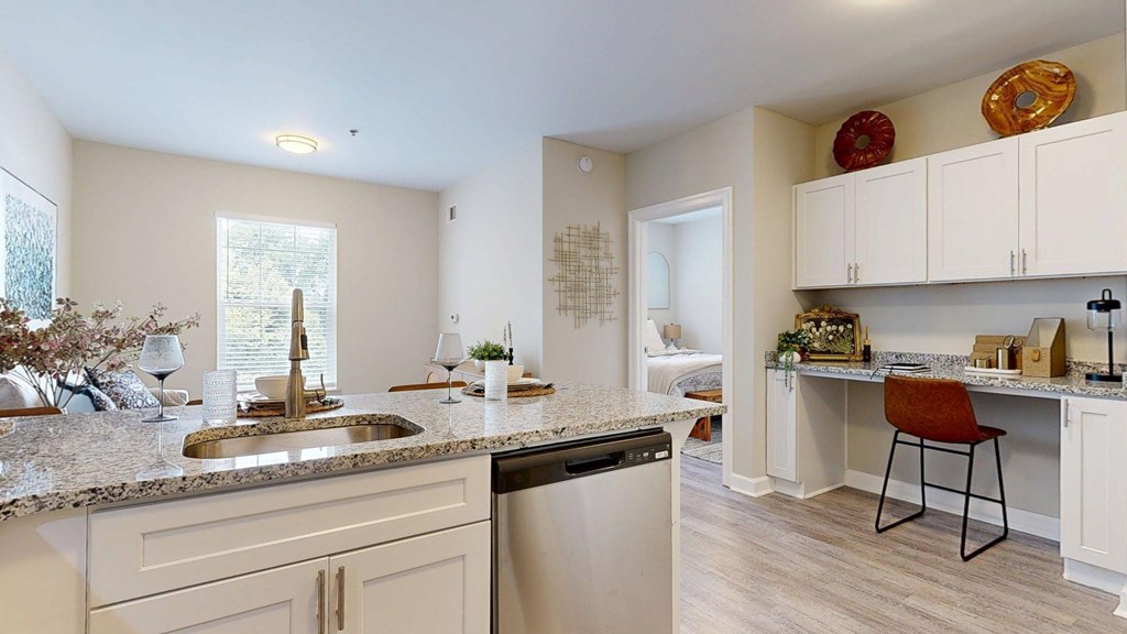 A kitchen with a sink, dishwasher, and a counter with a chair.
