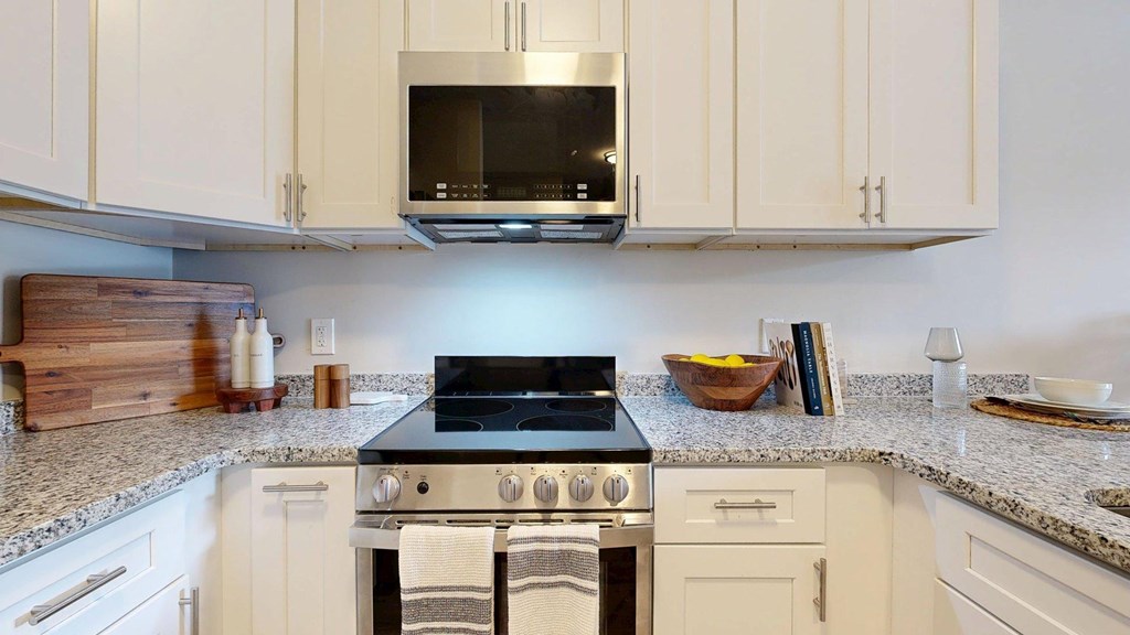 A kitchen with a black stove top oven and white cabinets.