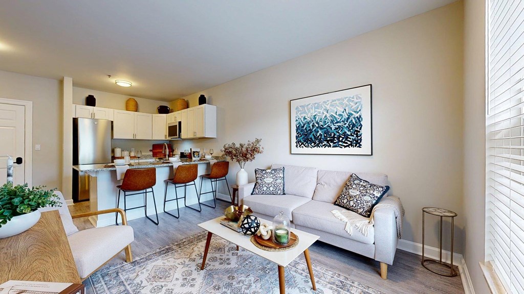 A living room with a white couch and a painting on the wall.