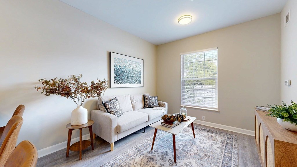 A living room with a couch, a coffee table, and a painting on the wall.