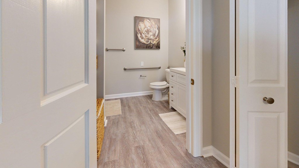 A bathroom with a toilet, sink, and a painting on the wall.