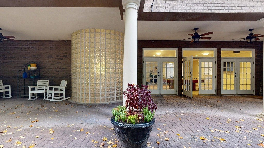 A patio with a white chair and a black planter.