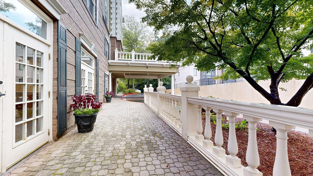 A white railing runs along the left side of a brick patio.