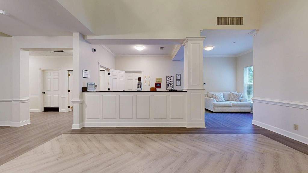 A spacious living room with a white sofa and a wooden floor.