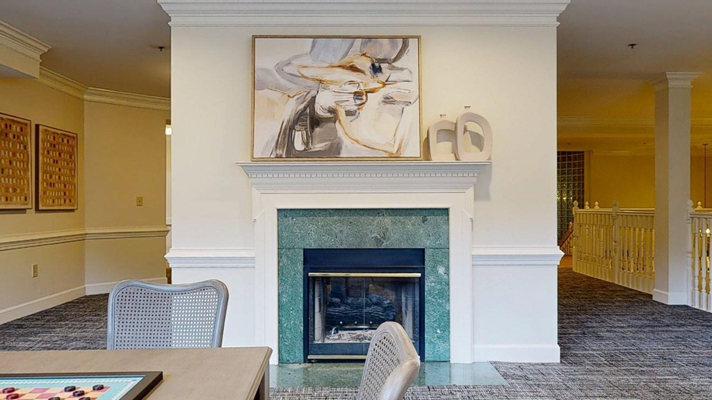 A painting hangs above a fireplace in a room with a table and chairs.