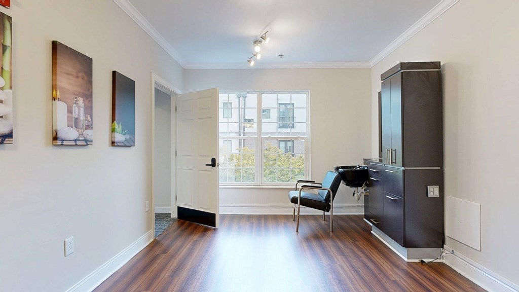 A black chair sits in front of a black refrigerator in a white room.