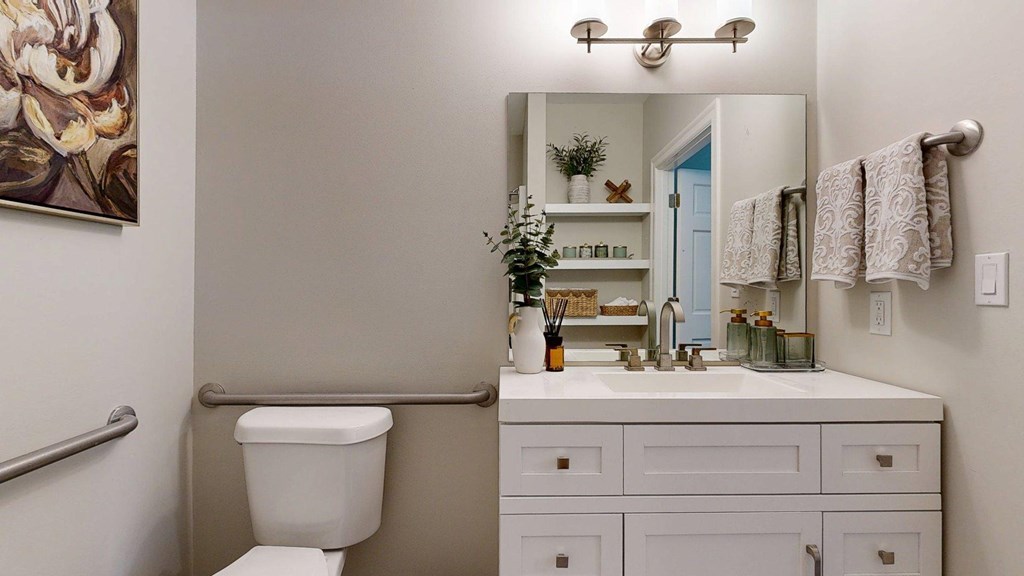 A bathroom with a toilet, sink, and mirror.