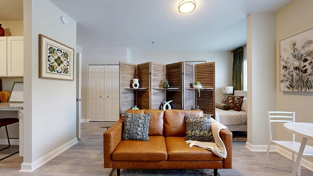 A living room with a brown couch and a white chair.