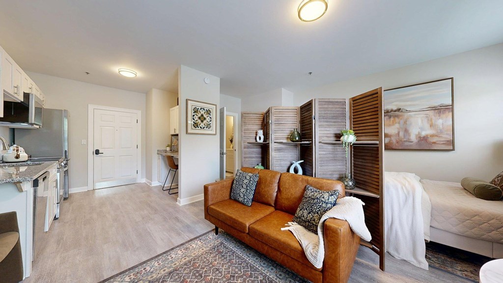 A living room with a brown couch and a painting on the wall.