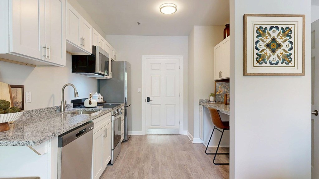 A kitchen with a granite counter top and stainless steel appliances.