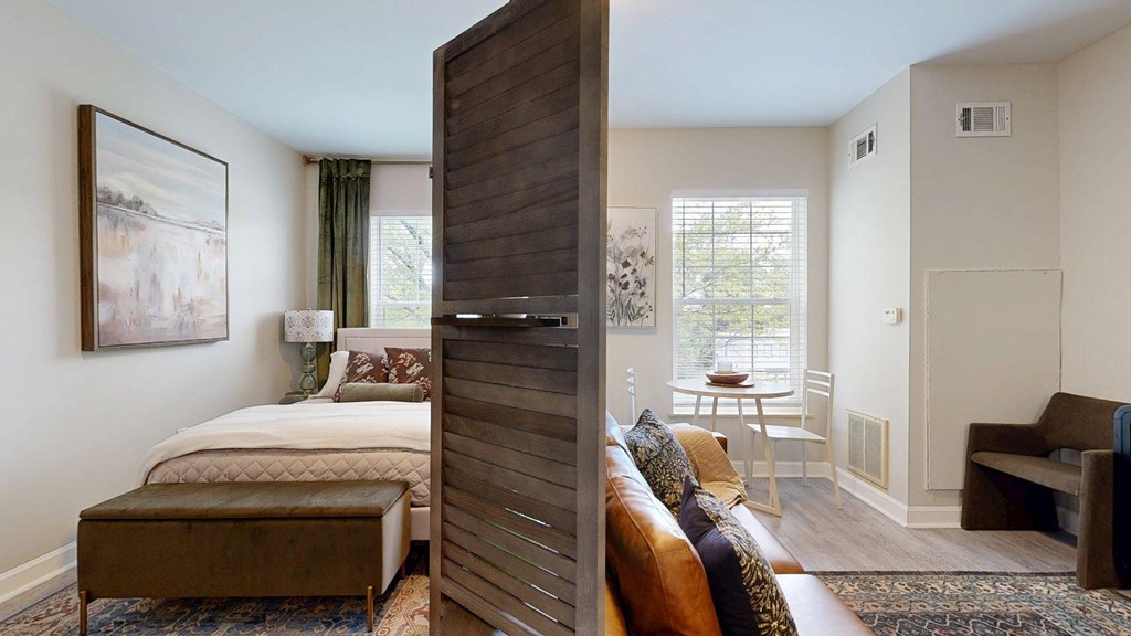 A bedroom with a large bed and a couch in the living room.