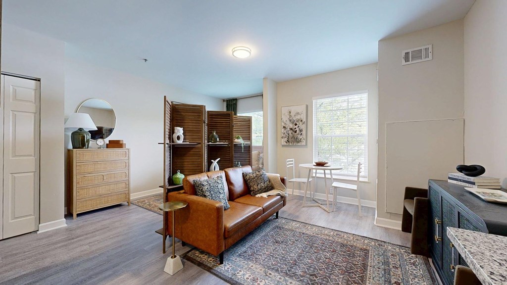 A living room with a brown couch and a rug.