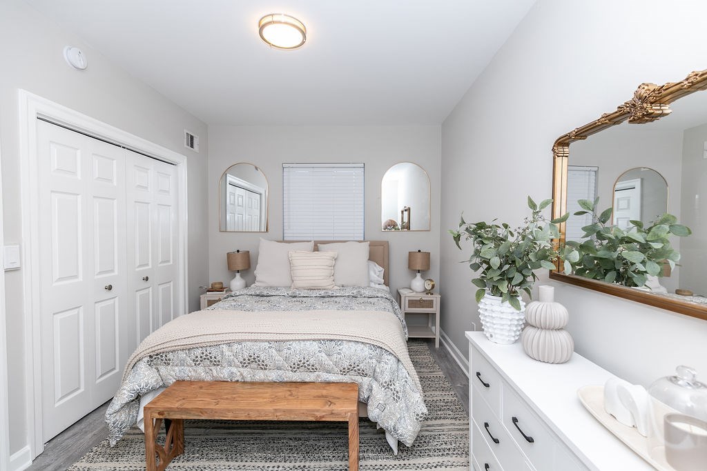 A bedroom with a bed, a bench, and a mirror.