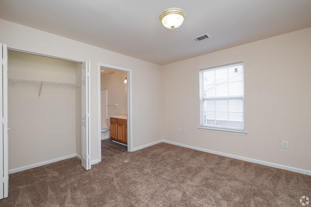 A room with a carpeted floor and a window with blinds.