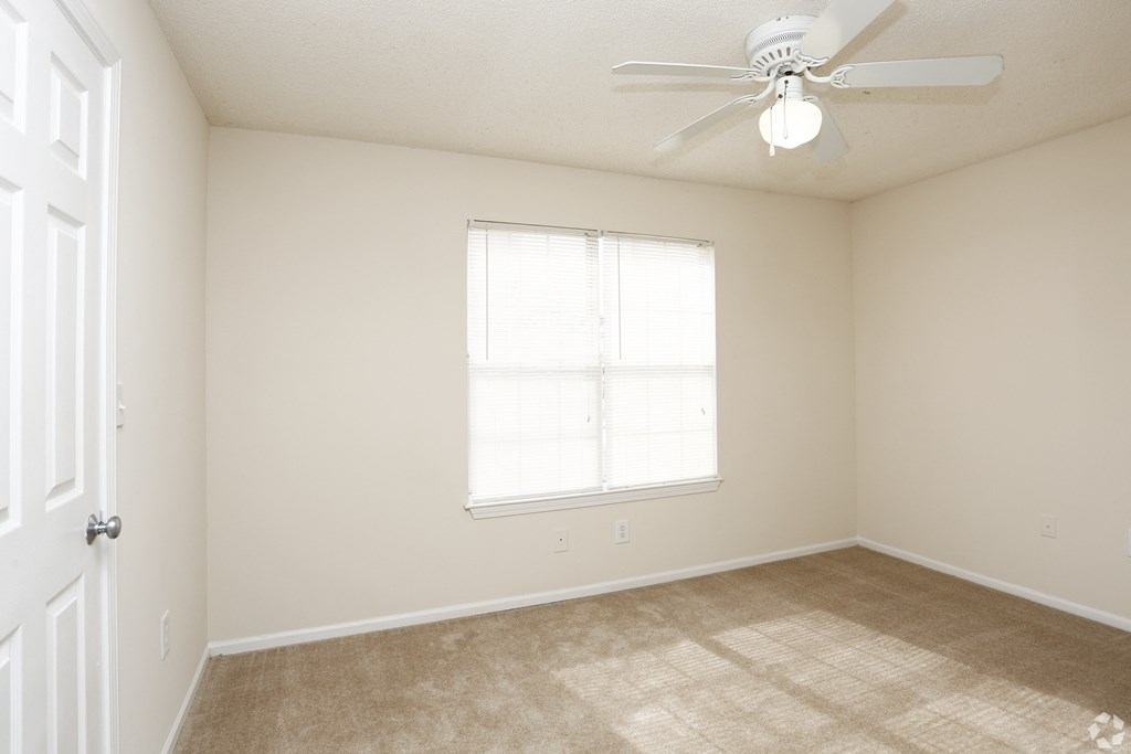 A room with a ceiling fan and a window.