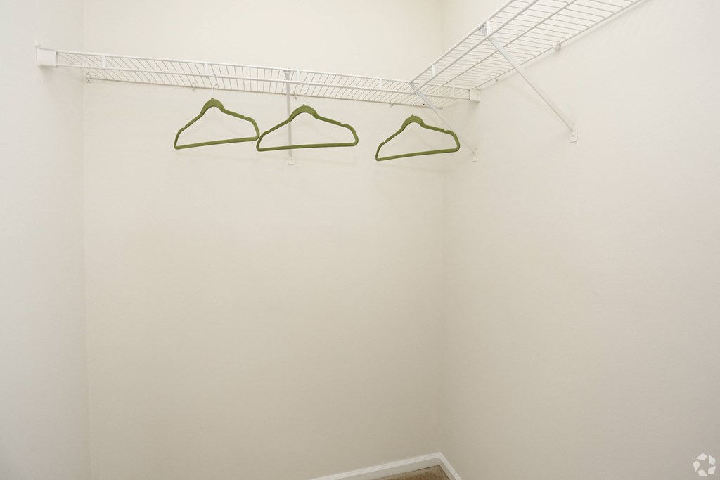 Three green hangers on a white wall.
