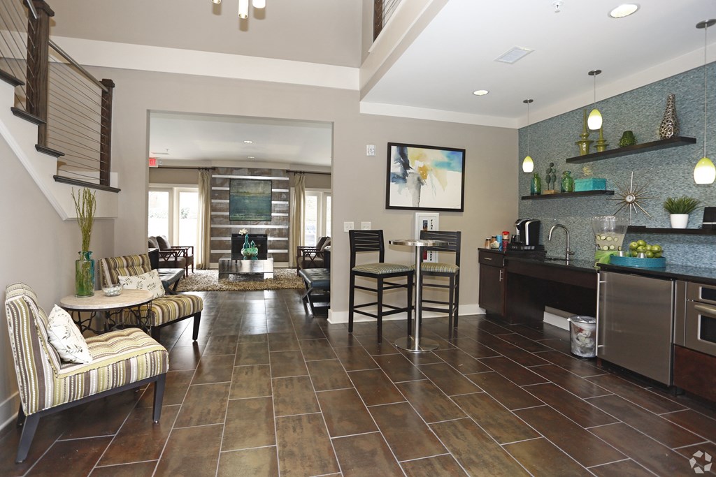 A living room with a striped couch and a kitchen area with a refrigerator and oven.