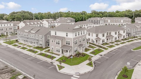 A large, modern residential complex with multiple buildings and a spacious parking lot.