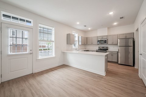A kitchen with white cabinets and a wooden floor.