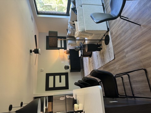 A modern living room with a white couch and a black chair.
