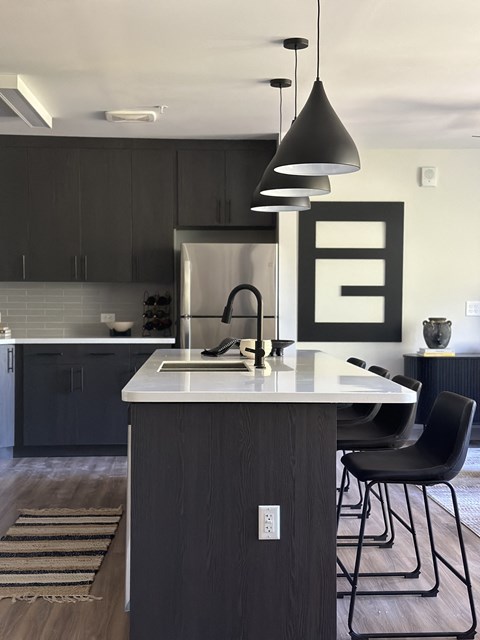 A modern kitchen with a dark wood island and chairs.