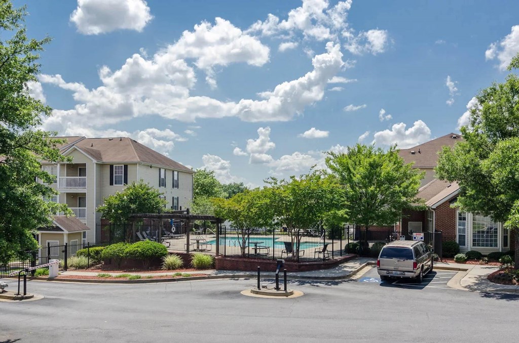 an empty parking lot with a swimming pool in front of apartment buildings