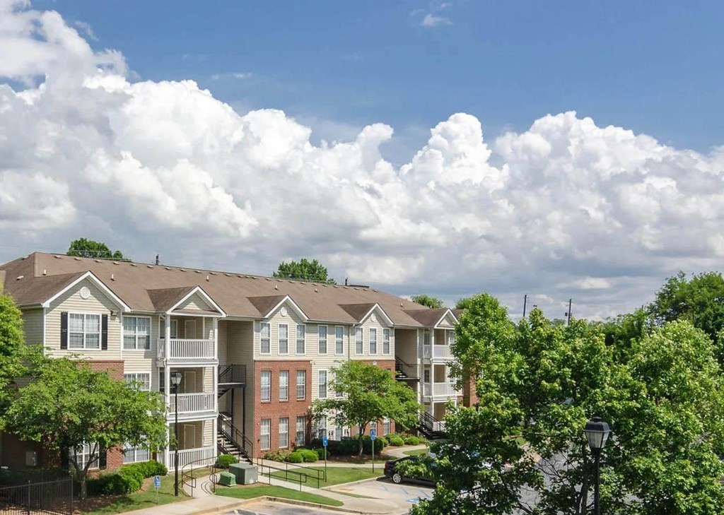 an apartment building with trees and a cloudy sky