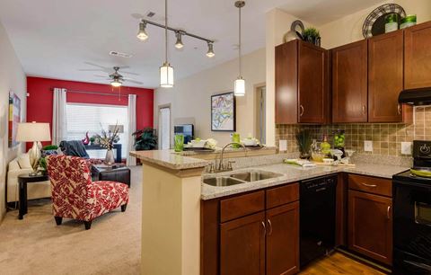 Kitchen with dining bar overlooking carpeted living room at Ashley Auburn Pointe in Atlanta, GA