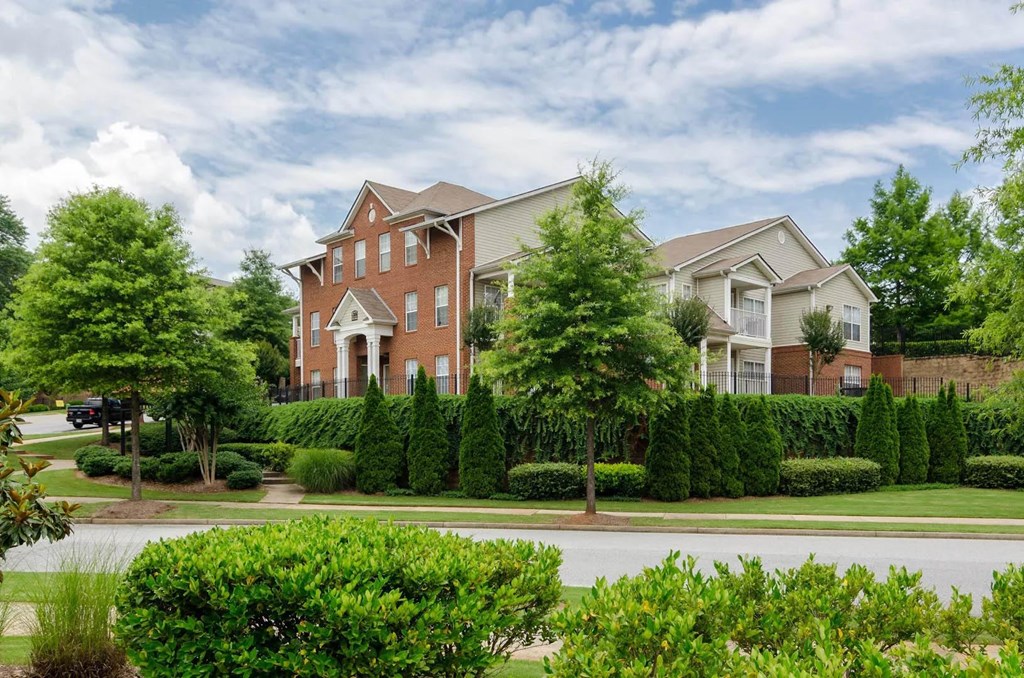 an apartment building on a street with trees and bushes