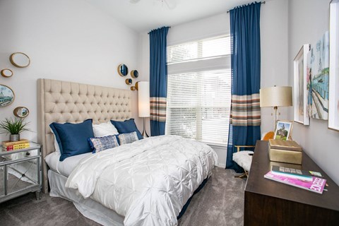 A bedroom with a large bed and a nightstand with a lamp.