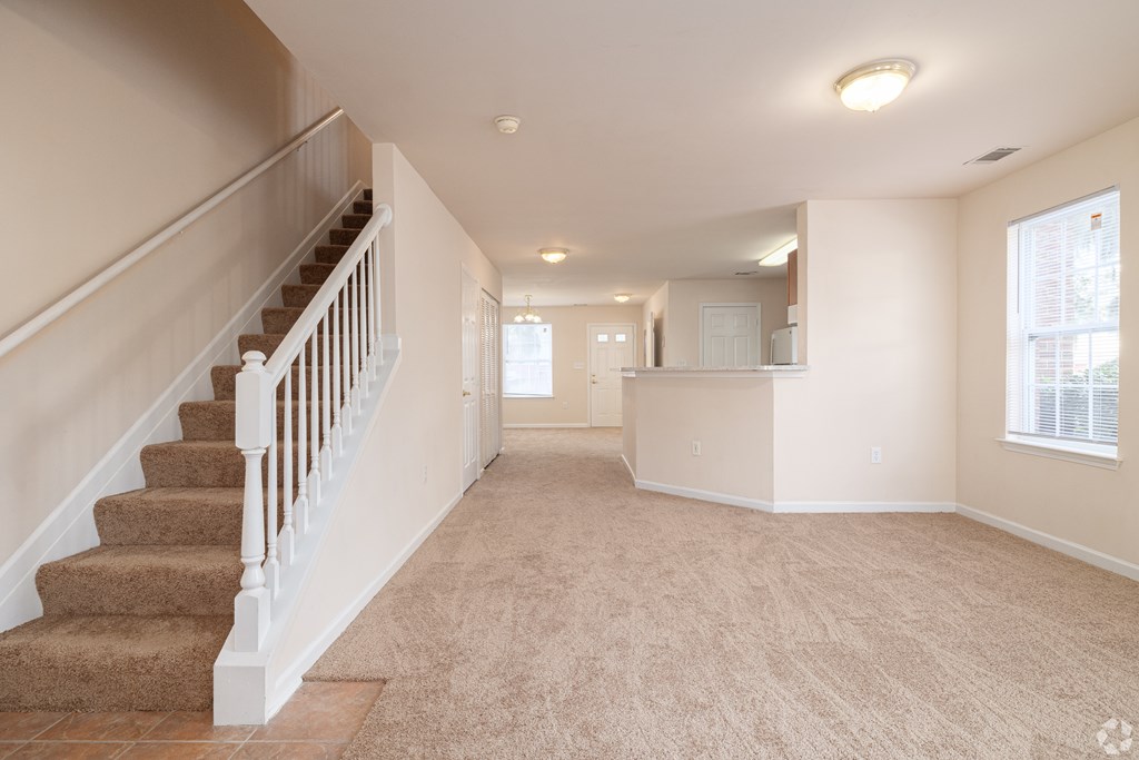 A spacious room with a staircase and carpeted floor.