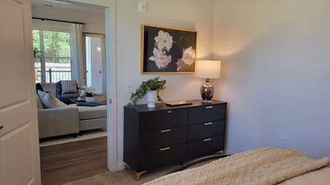 A bedroom with a black dresser and a painting on the wall.