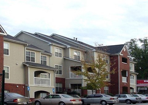 a row of apartment buildings with cars parked in a parking lot