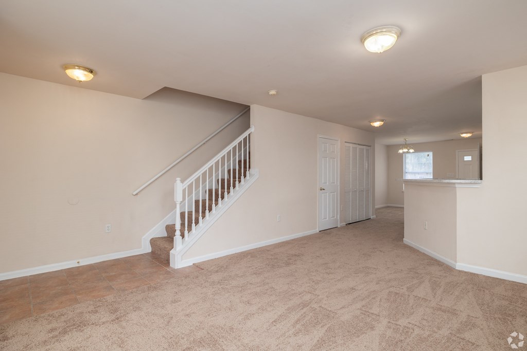 A spacious room with a staircase and a carpeted floor.