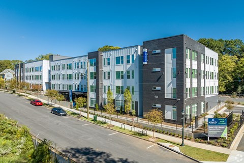 A modern multi-story building with a parking lot in front.