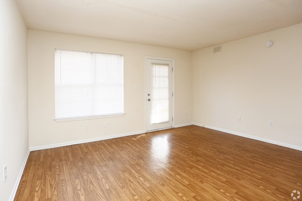 A room with wooden flooring and a door leading to another room.