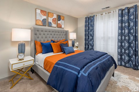 A bedroom with a large bed and a nightstand with a clock on it.